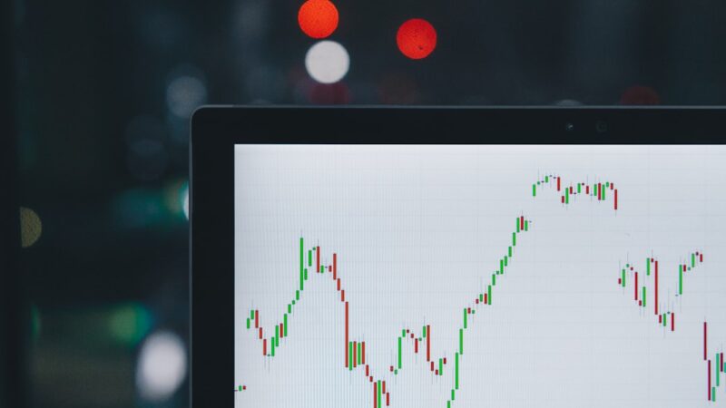 Close-up of a trading chart on a laptop screen with green and red candlestick patterns against a blurred background